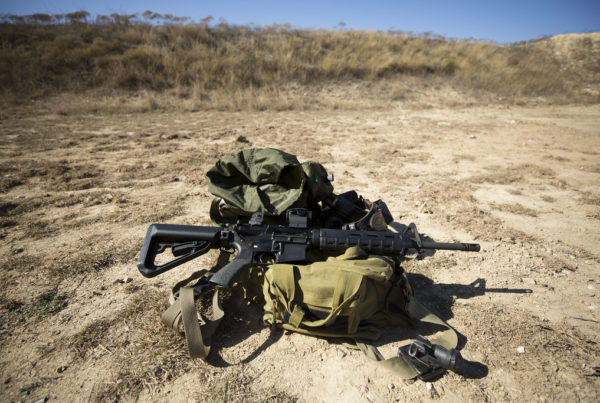 A cache of weapons and ammunition on dusty, desert ground