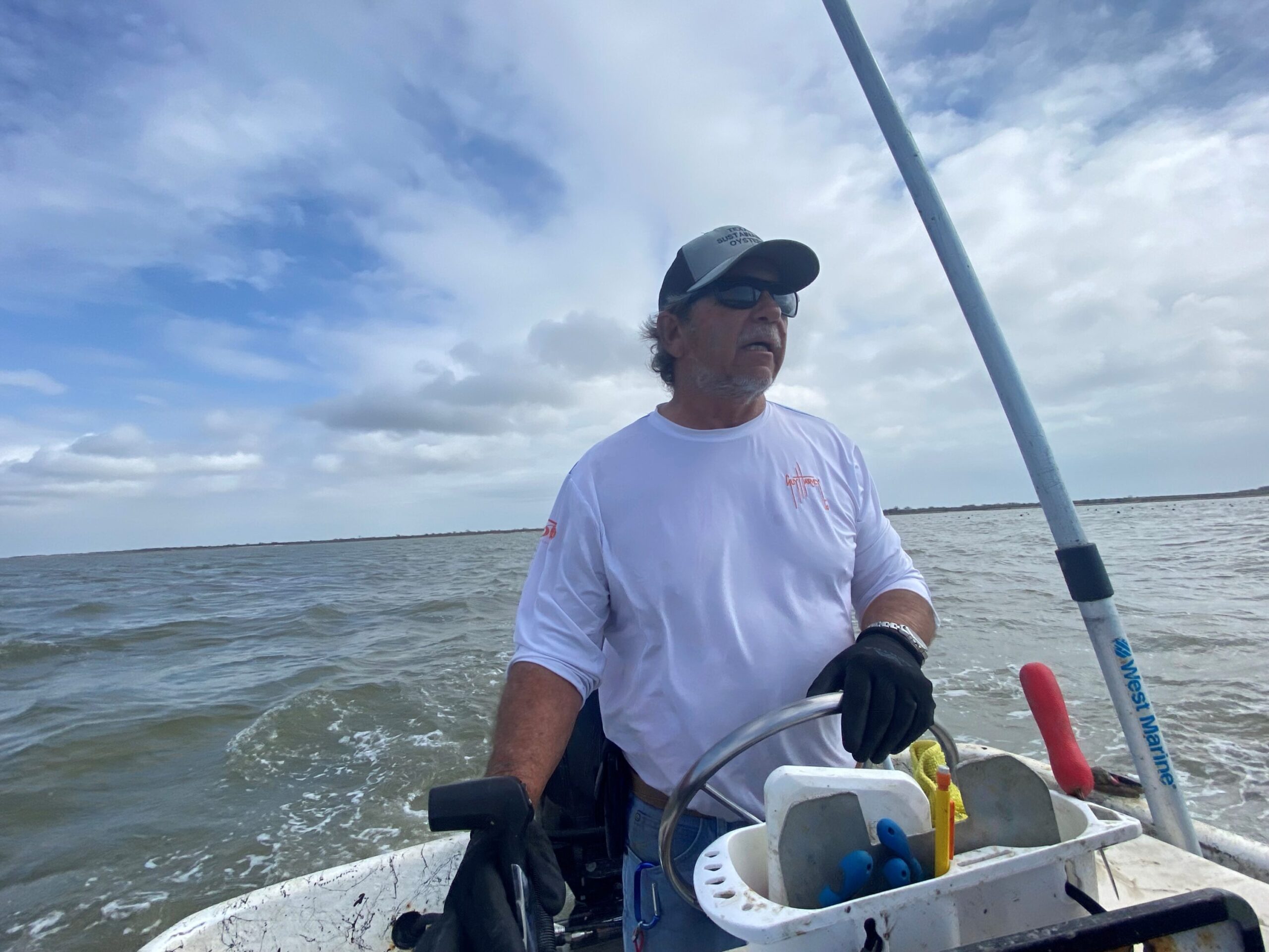 A man is seen at the steering wheel of a boar. He's seen from the front, the ocean behind him. This is Gordon Lipscomb.