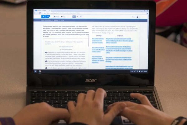 Three hands are seen at a laptop computer that's showing a practice exam