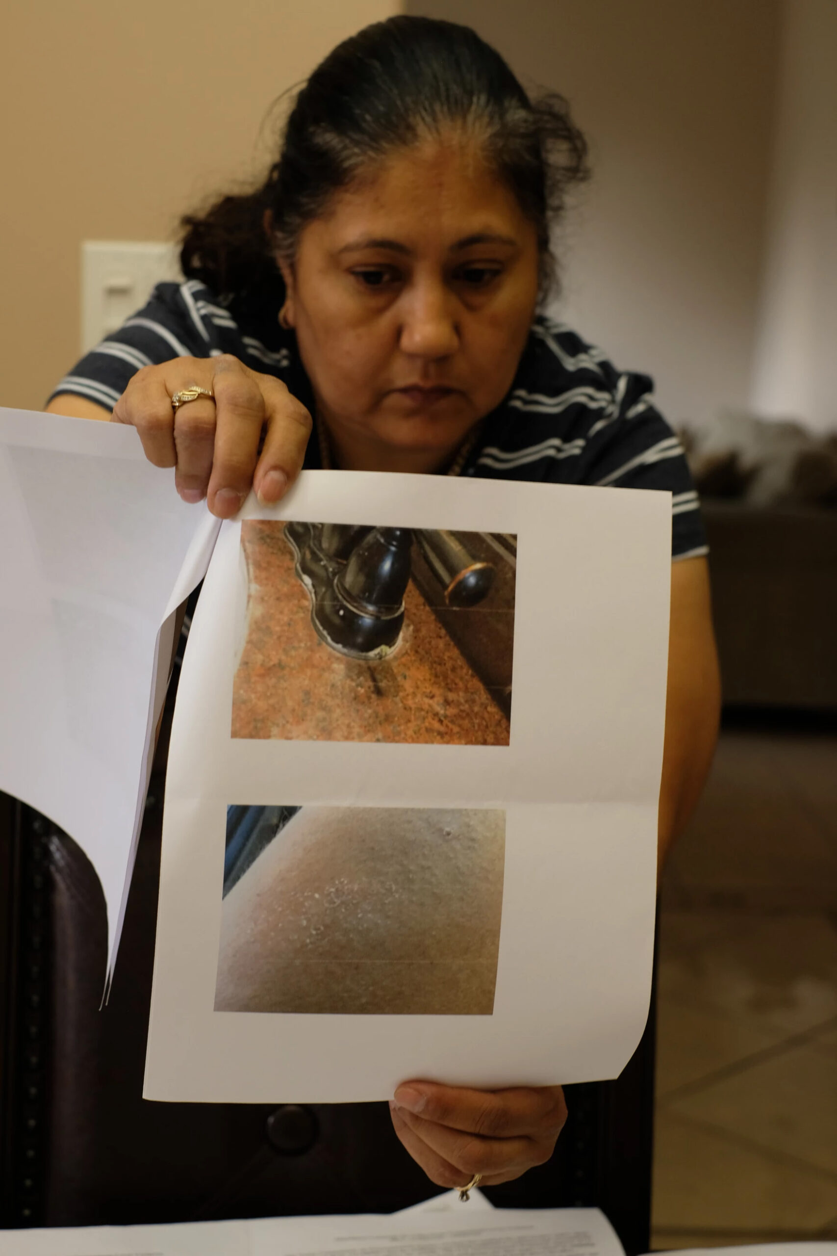Araceli Palomino holds up a sheet of paper in which two photos are printed. The top shows crust forming around a faucet base the other shows some discoloration on skin.
