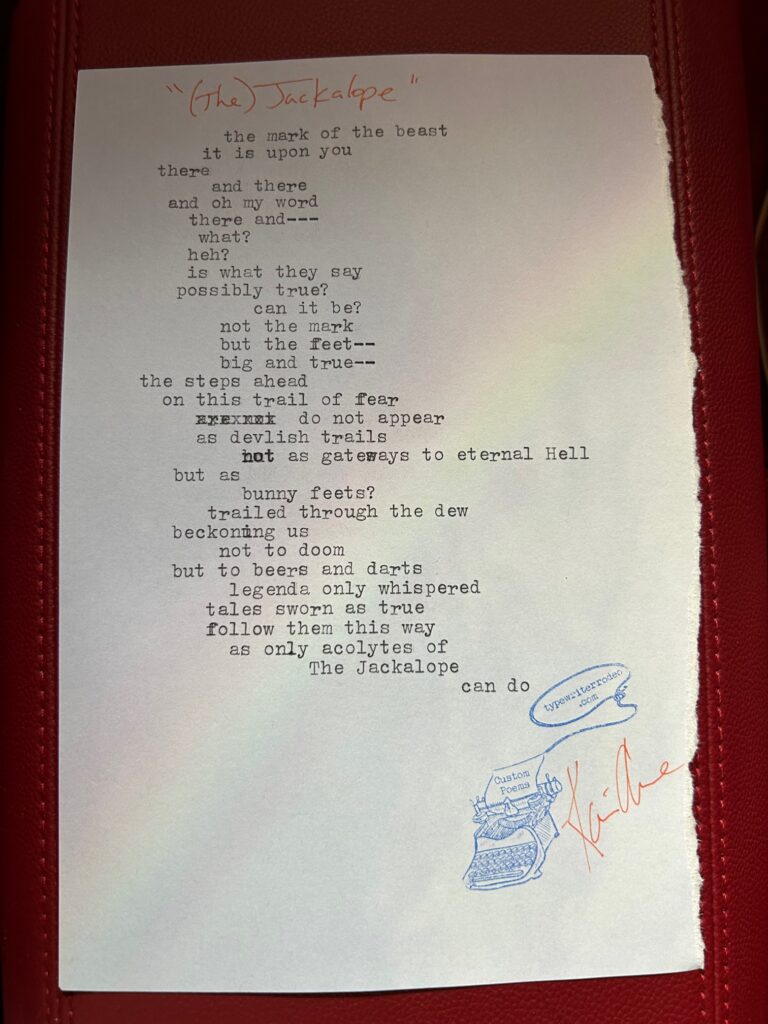a photo of the typewritten poem on a torn piece of lavender paper with a light image of a rainbow through it