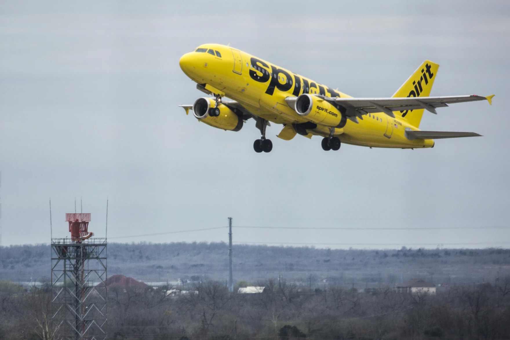 A yellow Spirit commercial airplane is seen mid-takeoff.
