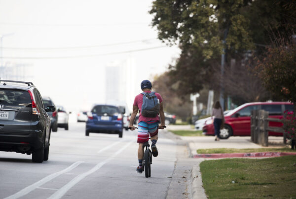 A cyclist bikes in a bike lane as alongside cars