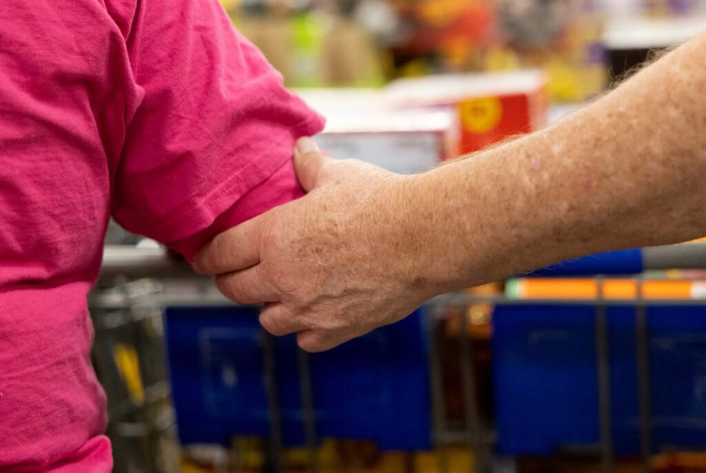 A close-up of a man's hand holding on to a woman's arm for guidance