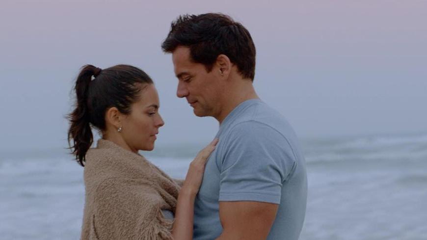 Two people embrace on a beach.