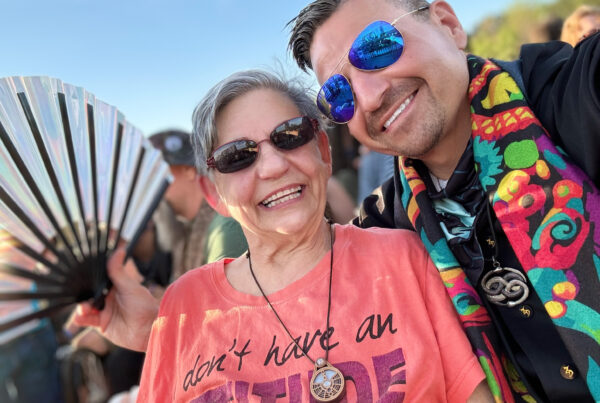 A man wearing sunglasses poses for a selfie with his mother.