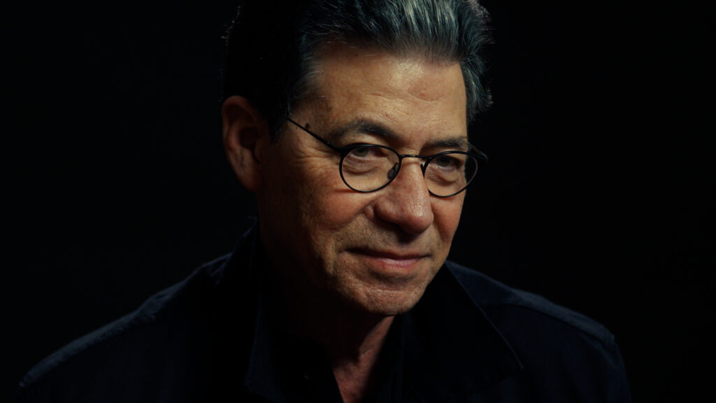 A man with classes looks at the camera.