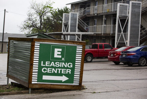 A large green sign outside an apartment building reads "leasing center" above an arrow pointing to the right
