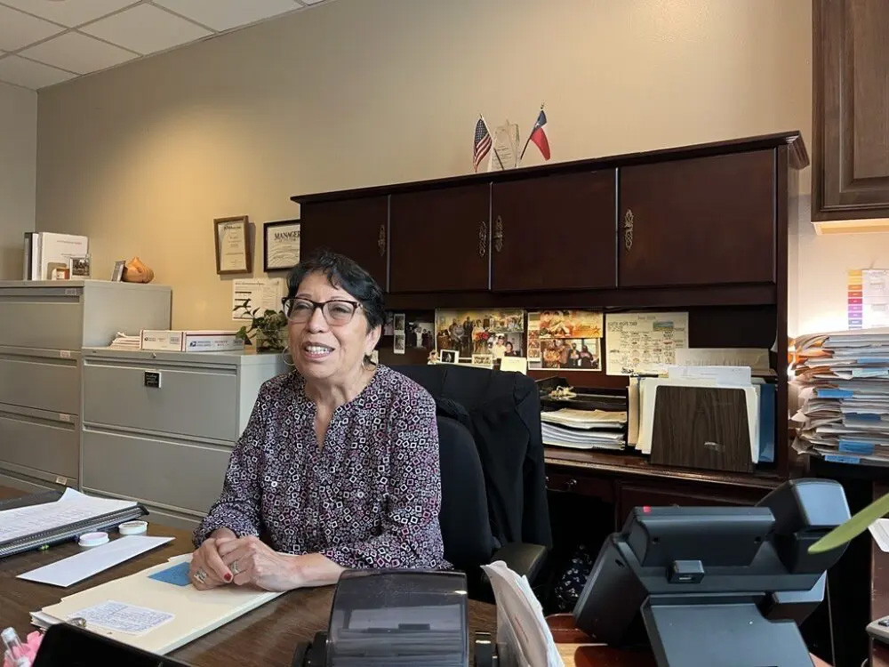 A woman smiles as she sits at her desk. This is Hope Aguirre.