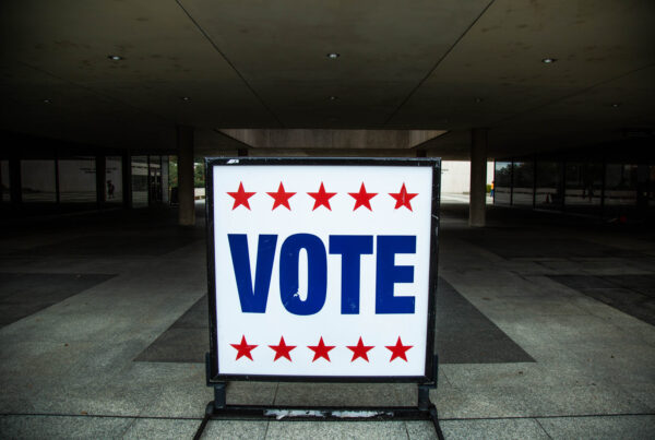A white sign that says VOTE in blue letters and has a row of five red stars both above and below