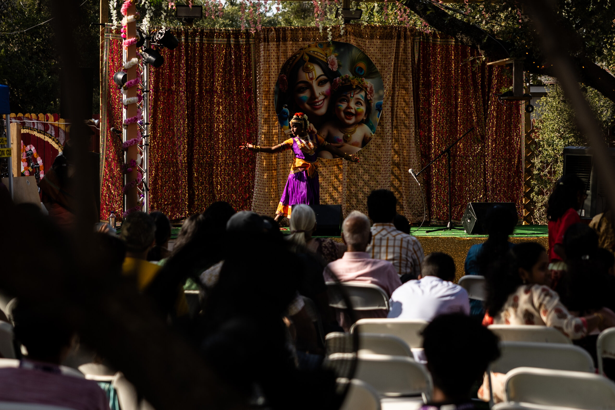 A person dances in traditional garb before a seated crowd.