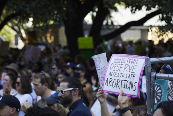 A person holds a sign that reads "Young people deserve access to safe abortions"