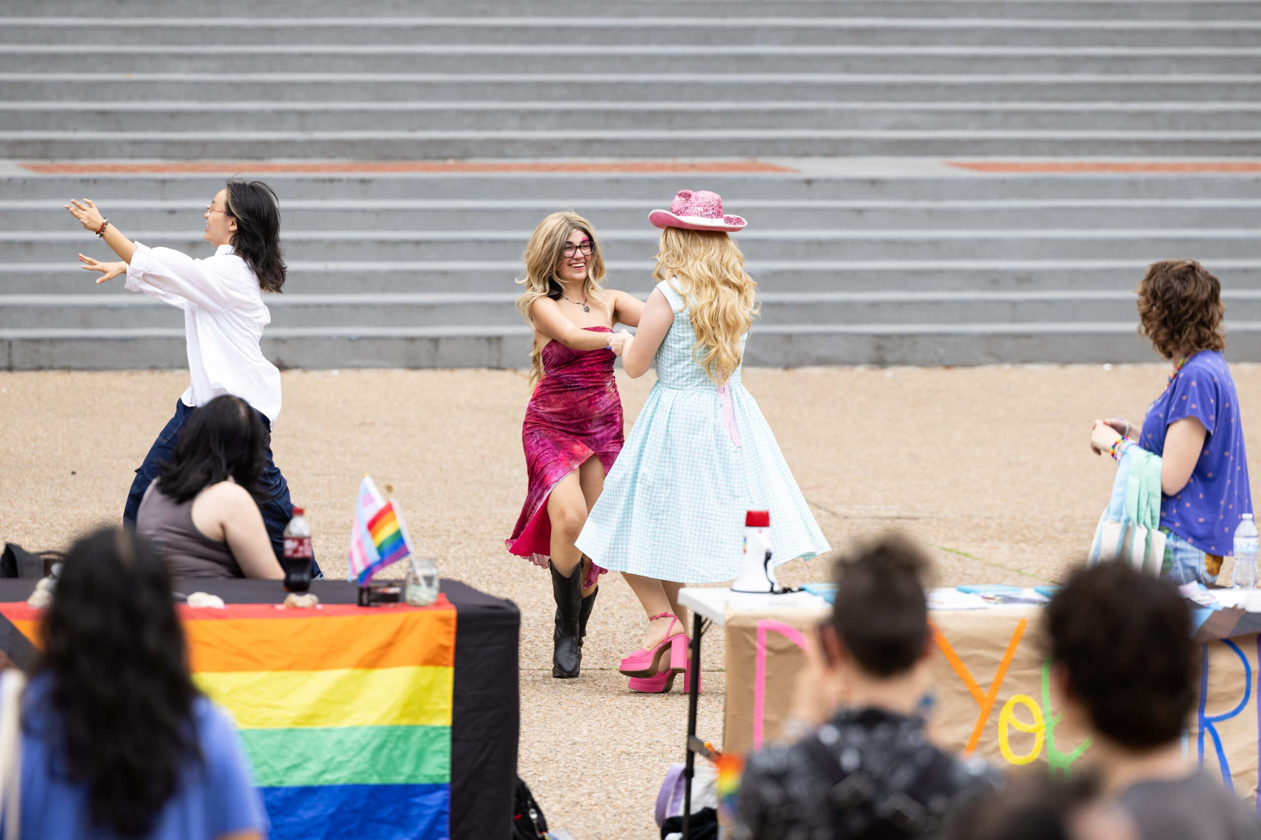 Students wearing western boots, hats and dresses dance as others look on.