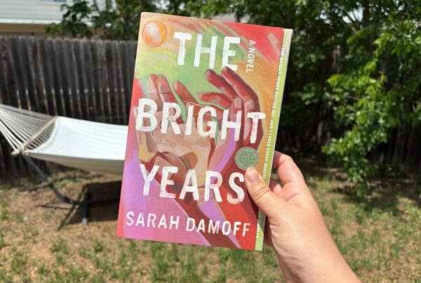 The book "The Bright Years" by Sarah Damoff is held up outside in front of a hammock