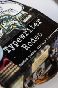 A close-up photo of a typewriter case with stickers on it.