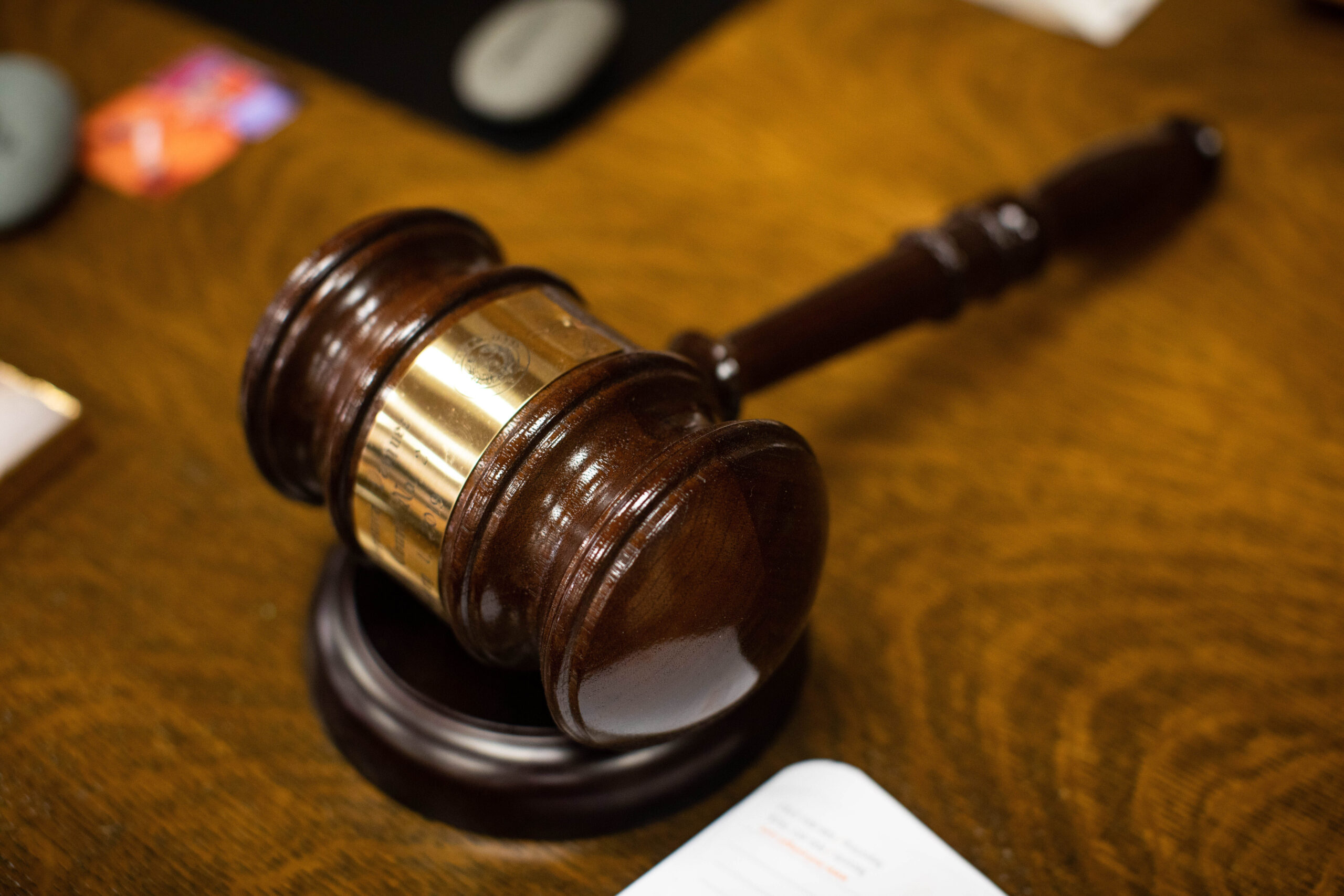 A close-up of a wooden gavel resting on a desk.