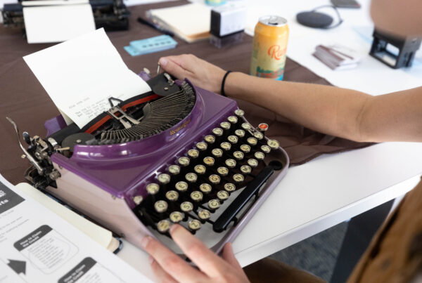 A close-up of someone typing a poem on a purple typewriter