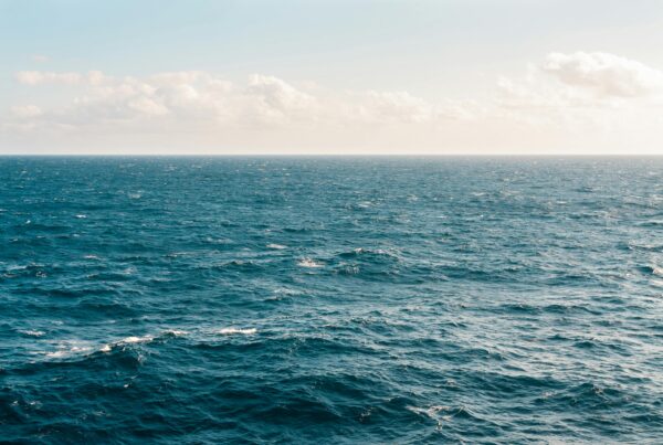A view of ocean and white clouds amid a blue sky