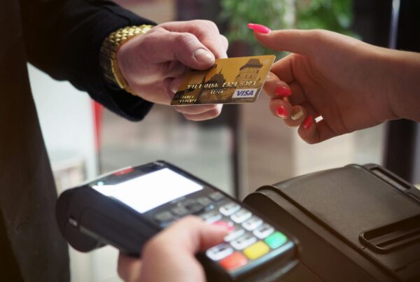 A closeup of a credit card being handed to someone holding a payment terminal