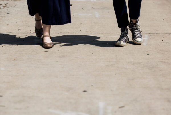 A close-up of two people's feet walking on a sidewalk