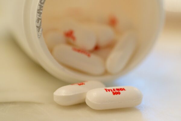 Tylenol pills are seen next to an open medicine bottle