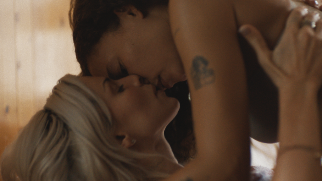 A still image from the film "Perfect" shows two people kissing.