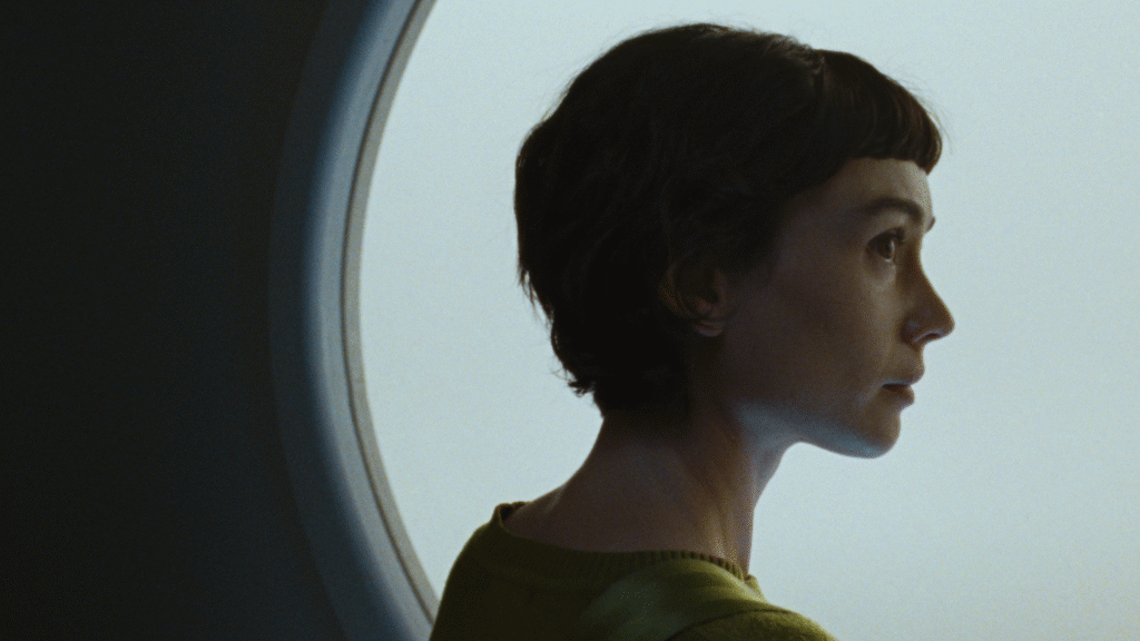 Actress Sydney Chandler looks to her right in front of a window in a still image from the film "Anima."