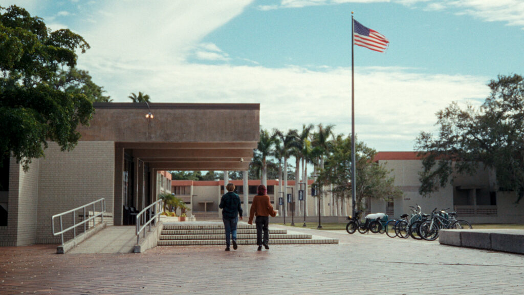 Two people walk on a college campus in a still image from the film "First They Came for My College:
