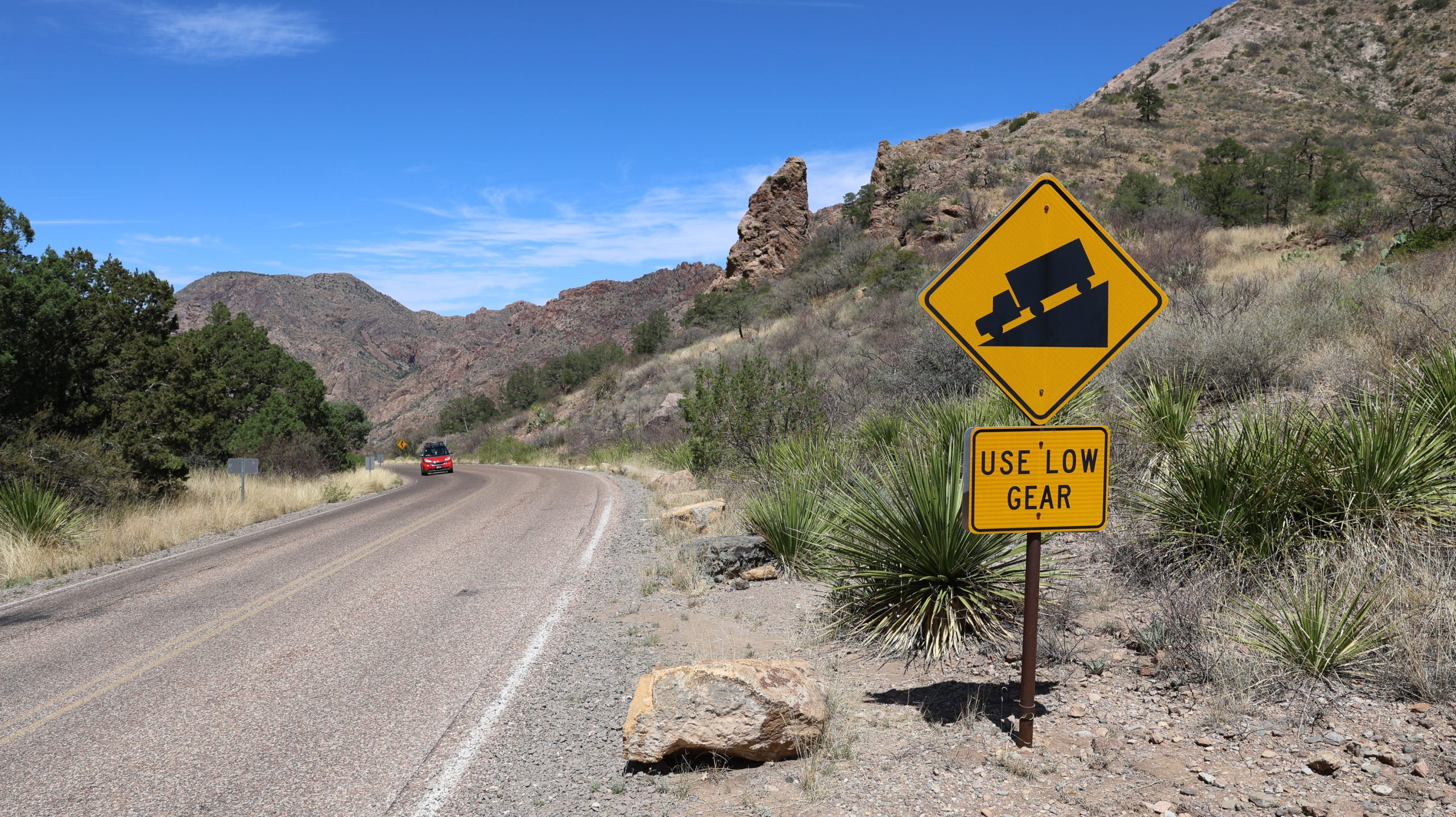 A winding roadway is seen next to a sign reading 
