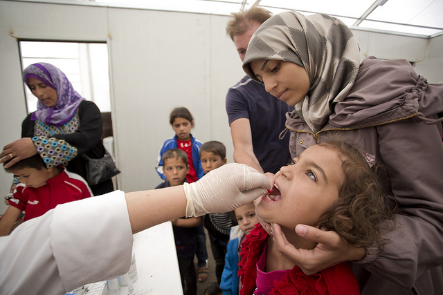 Fatima Bayoud, a Syrian refugee (top right) has her child, Ibtihaj vaccinated as they seek assistance from UNHCR, at refugee registration center near Tripoli, Lebanon on June 2, 2014. 