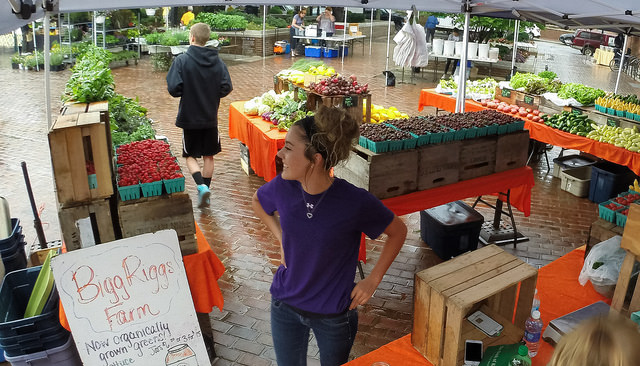 Shaylyn Bohrer looks out across the Old Town Market Square, ready for Bigg Riggs Farm customers, at the historic Old Town Farmers' Market, in Alexandria, Va.