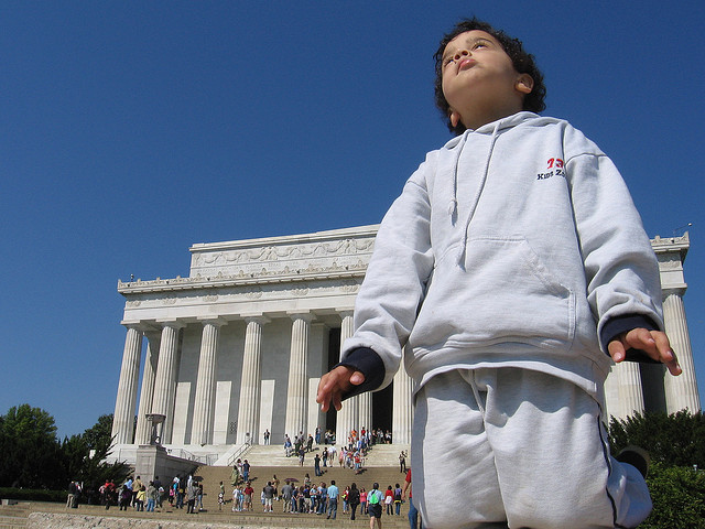 A child stands in front of the Lincoln Memorial and looks towards the direction of the Washington Monument and U.S. Capitol.