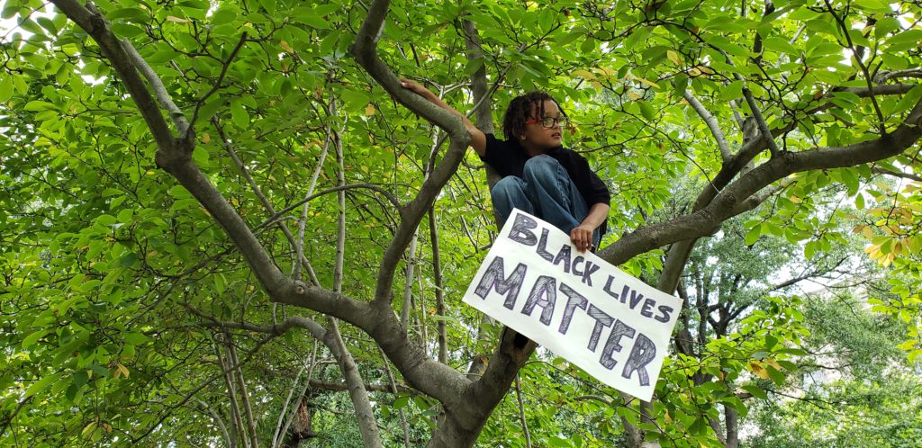 Elijah Harris, 10, of New York, carries his sign into a tree. 