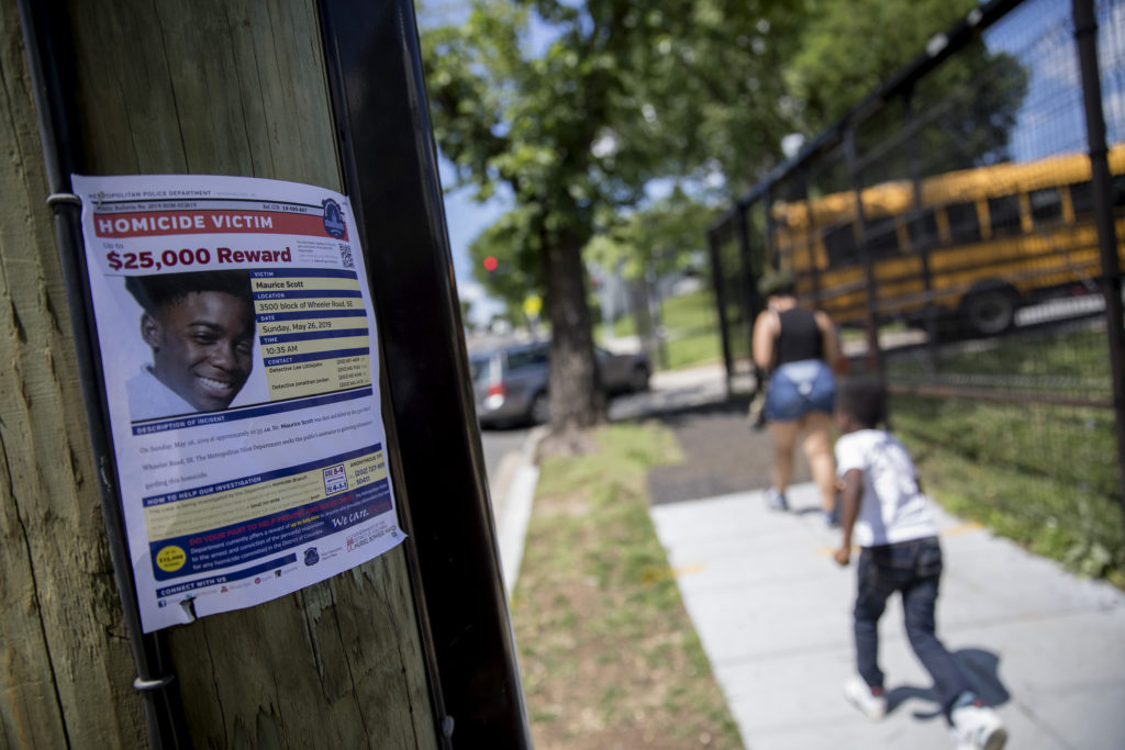 A sign is posted outside of Eagle Academy Public Charter School in Washington, D.C., requesting information regarding the shooting death of 15-year-old Maurice Scott, who was killed near the school over Memorial Day weekend. 