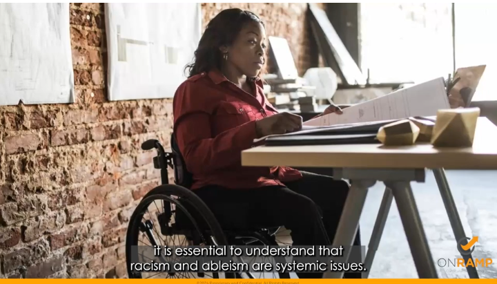 Wheelchair user at a desk reading papers. 