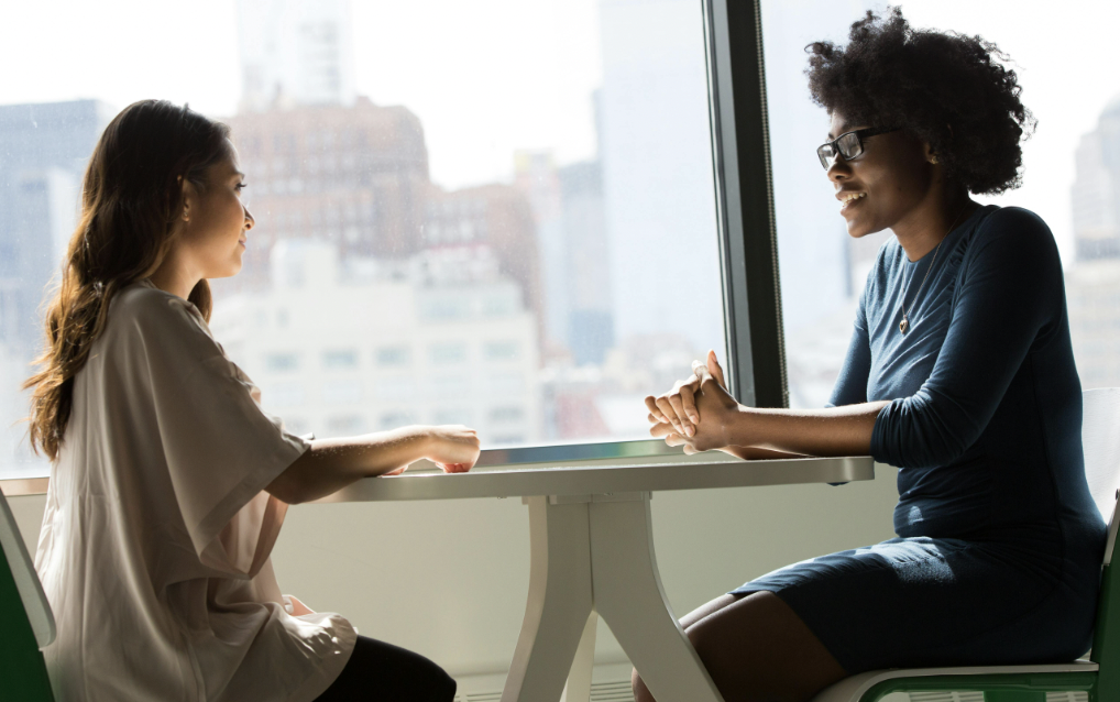 Two people sitting across from each other during a disagreement or conflict and talking through and resolving it 