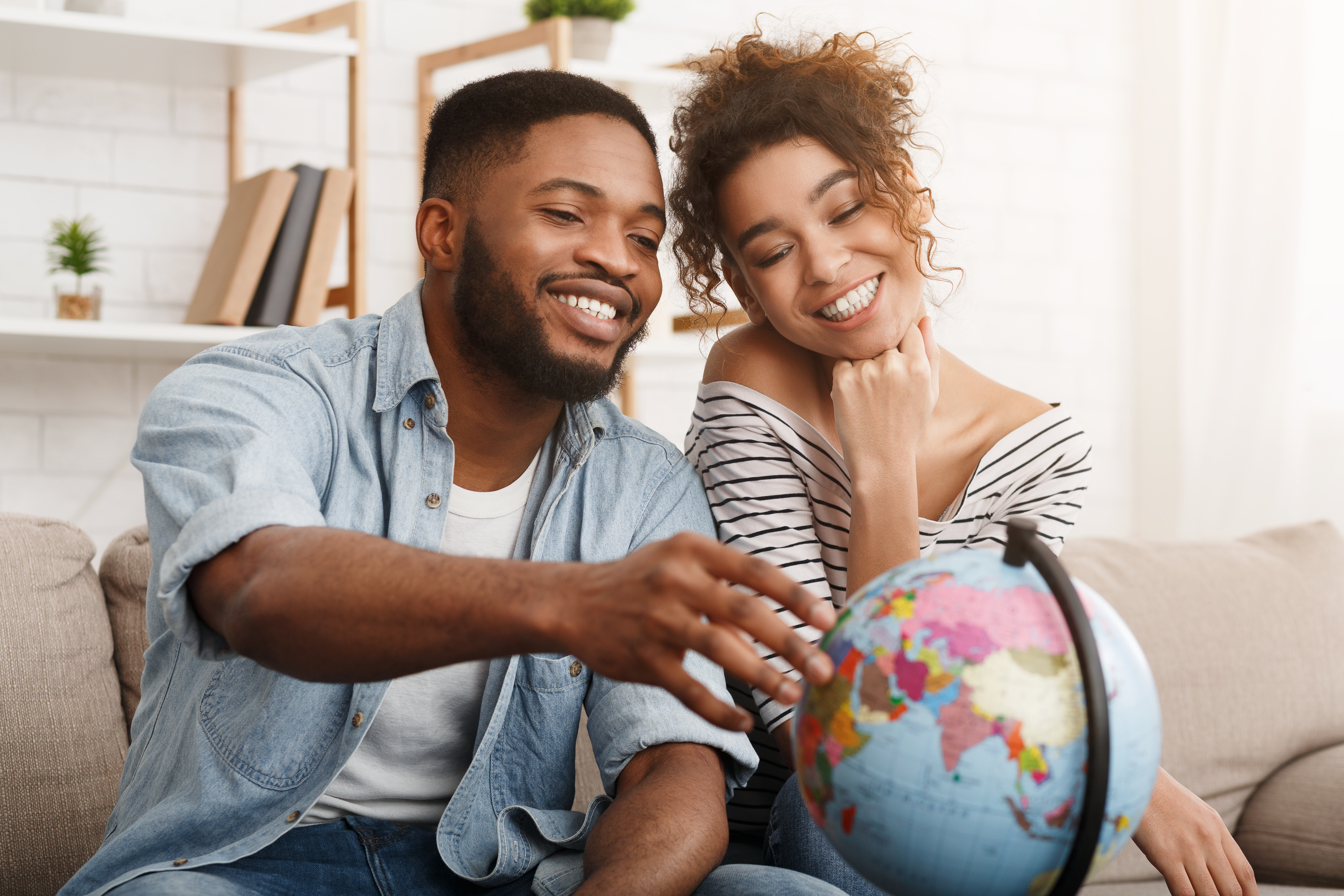 Millennial couple looking at globe and thinking about financial freedom