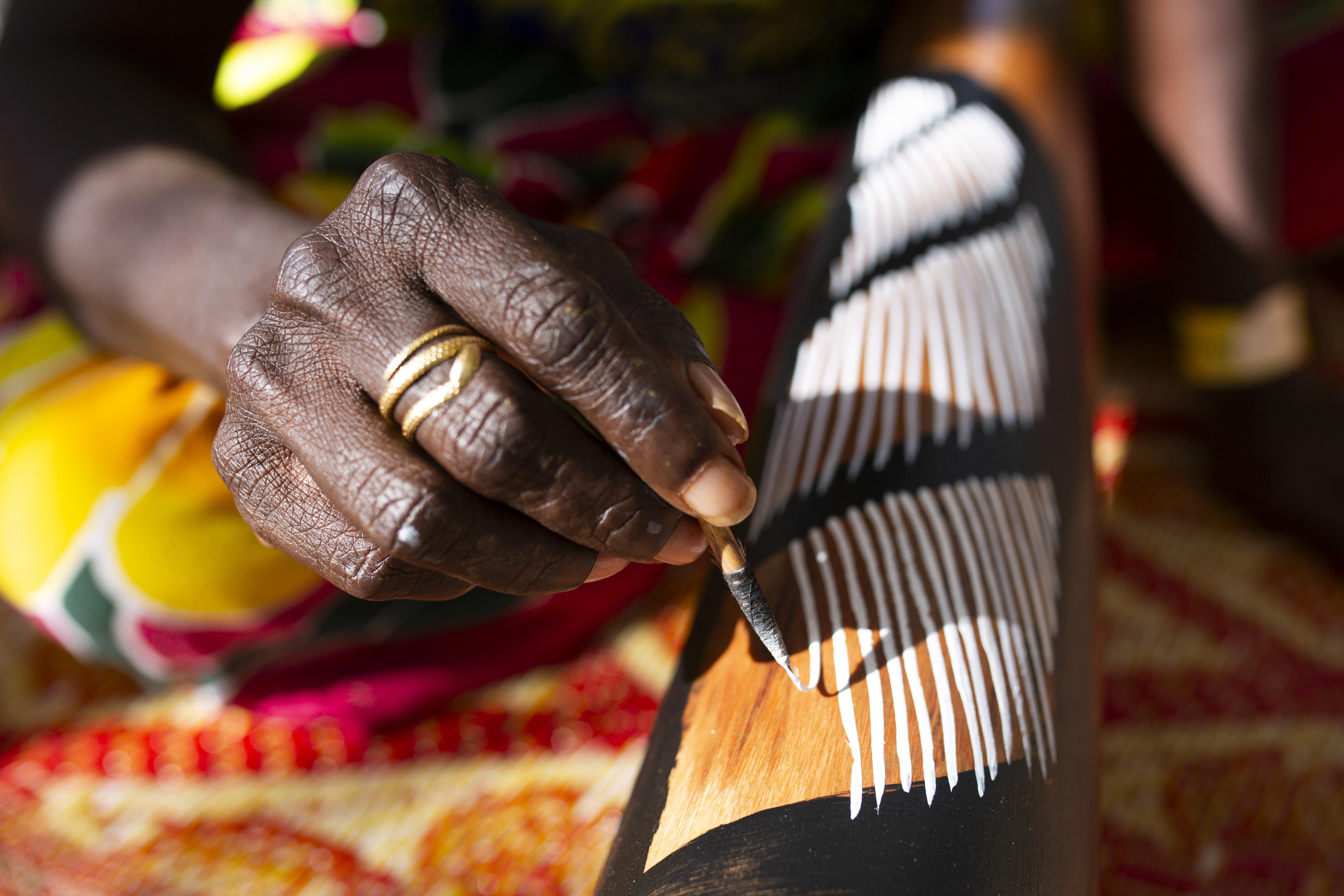 A woman paints a yidaki (didgeridoo).