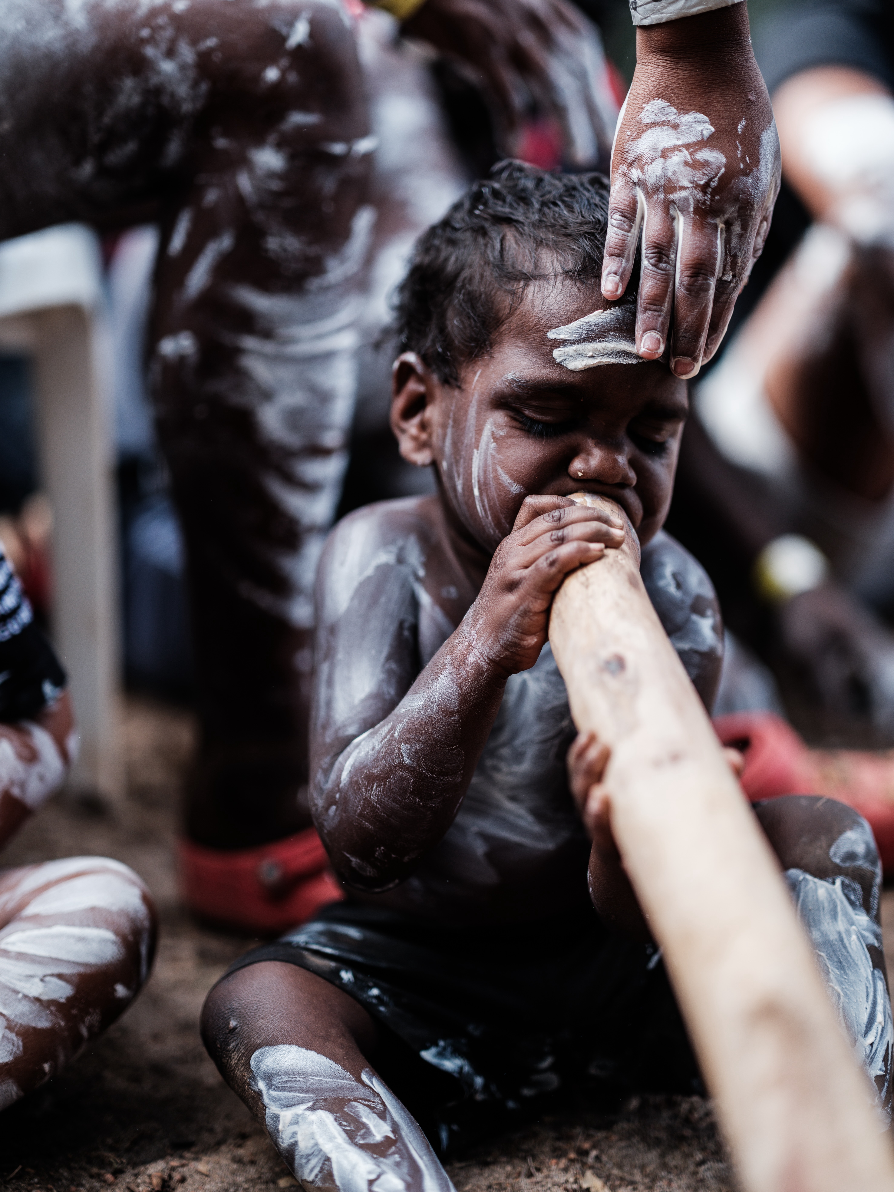 A young boy plays the yidaki (didgeridoo).