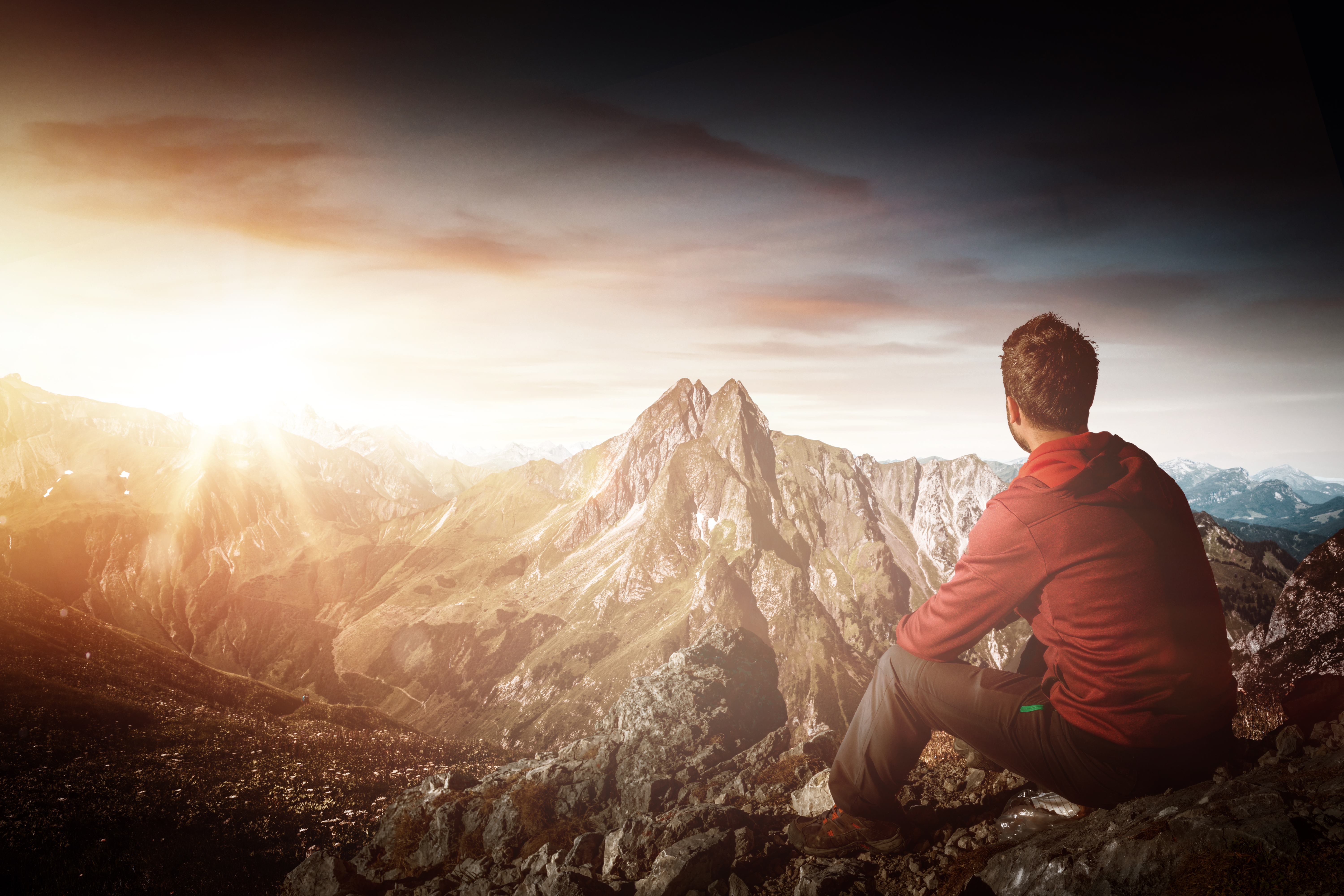 Man standing on a mountain peak, embracing freedom and a new life of transformation and limitless potential.