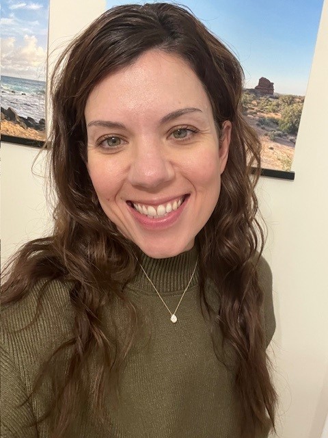 female with brown hair and green shirt smiling