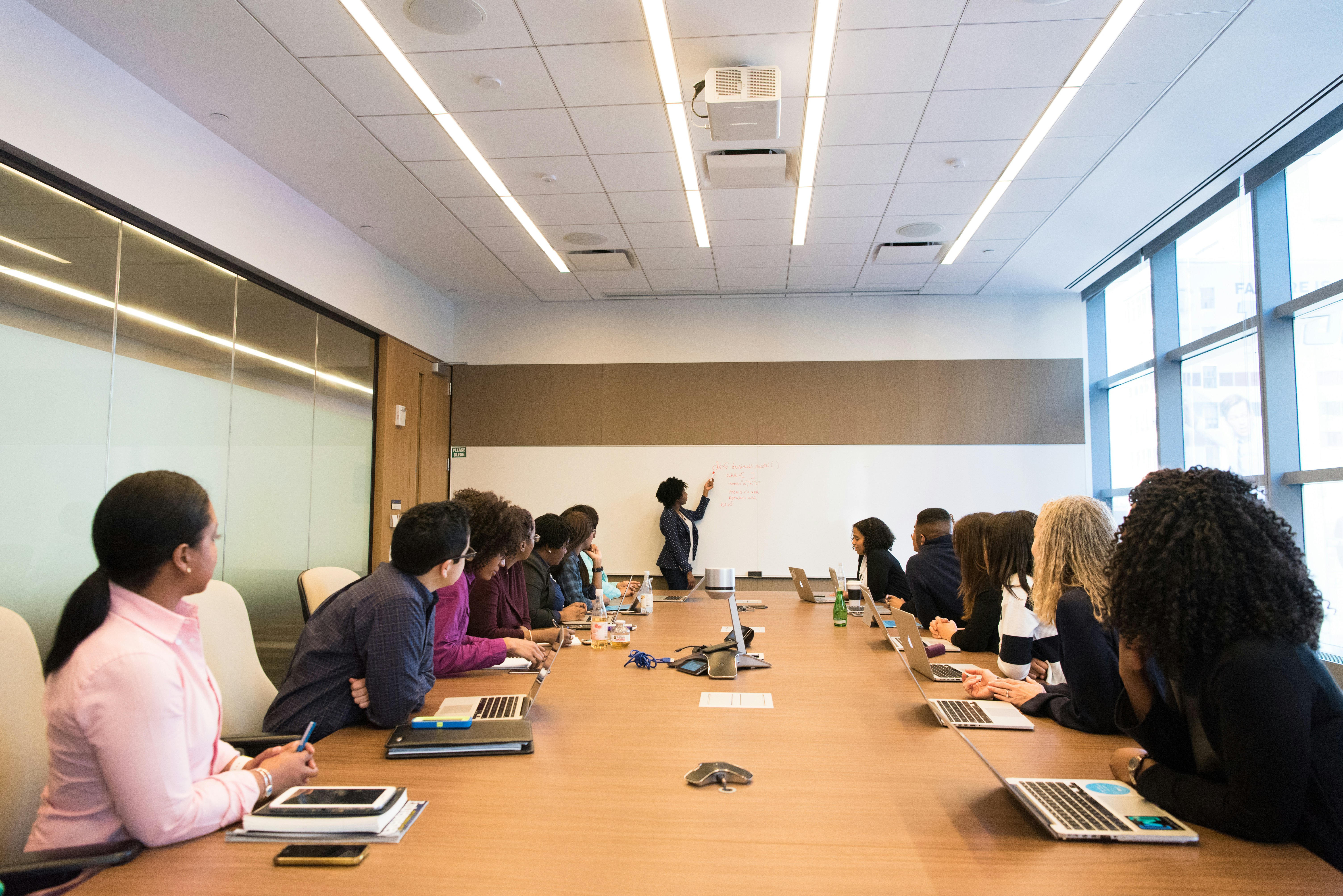 Woman confidently presenting to a boardroom full of people, illustrating leadership presence and strategic impact.
