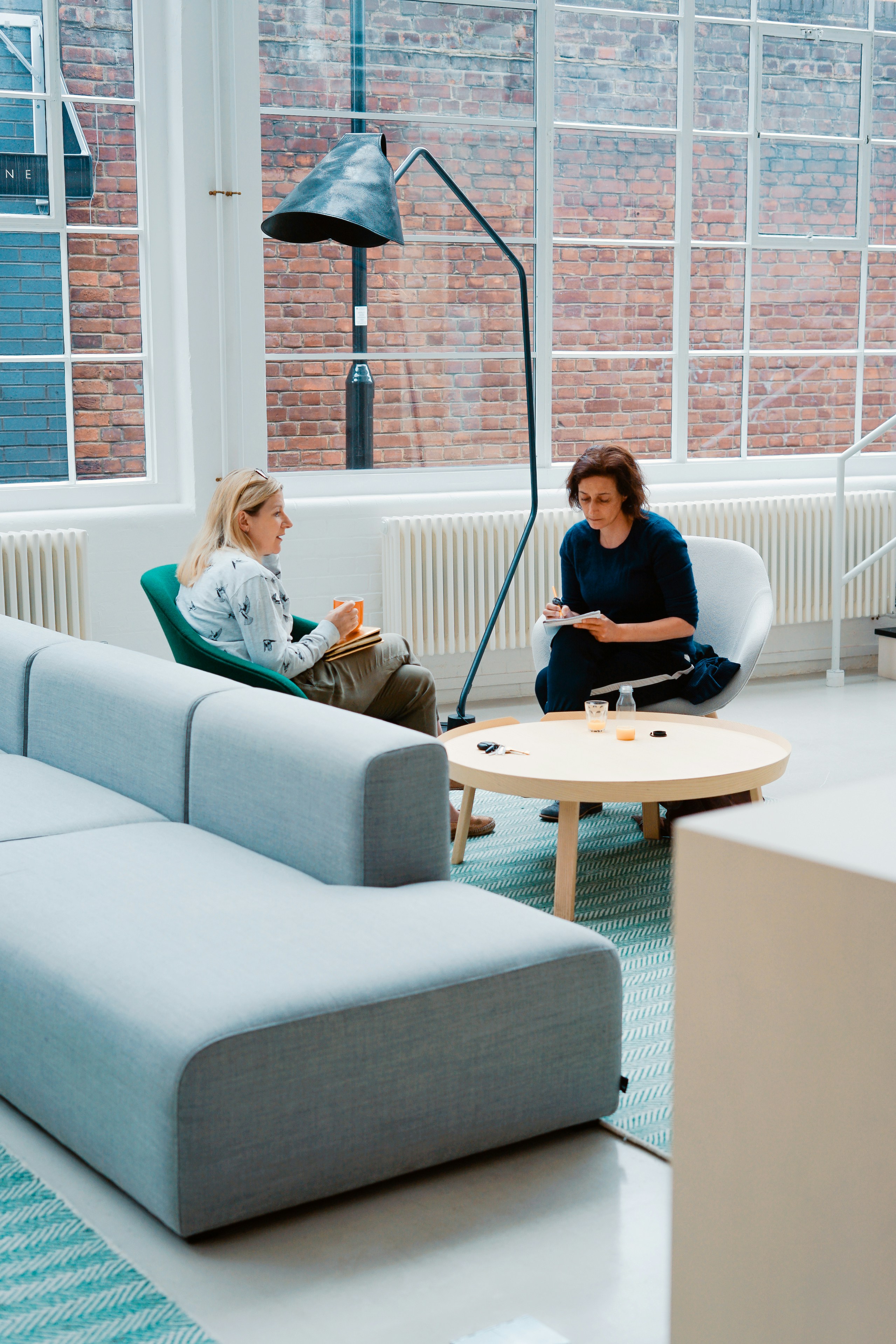 Two women meeting over coffee in a stylish office space, reflecting the personalized guidance and connection central to LeadWell’s coaching program.
