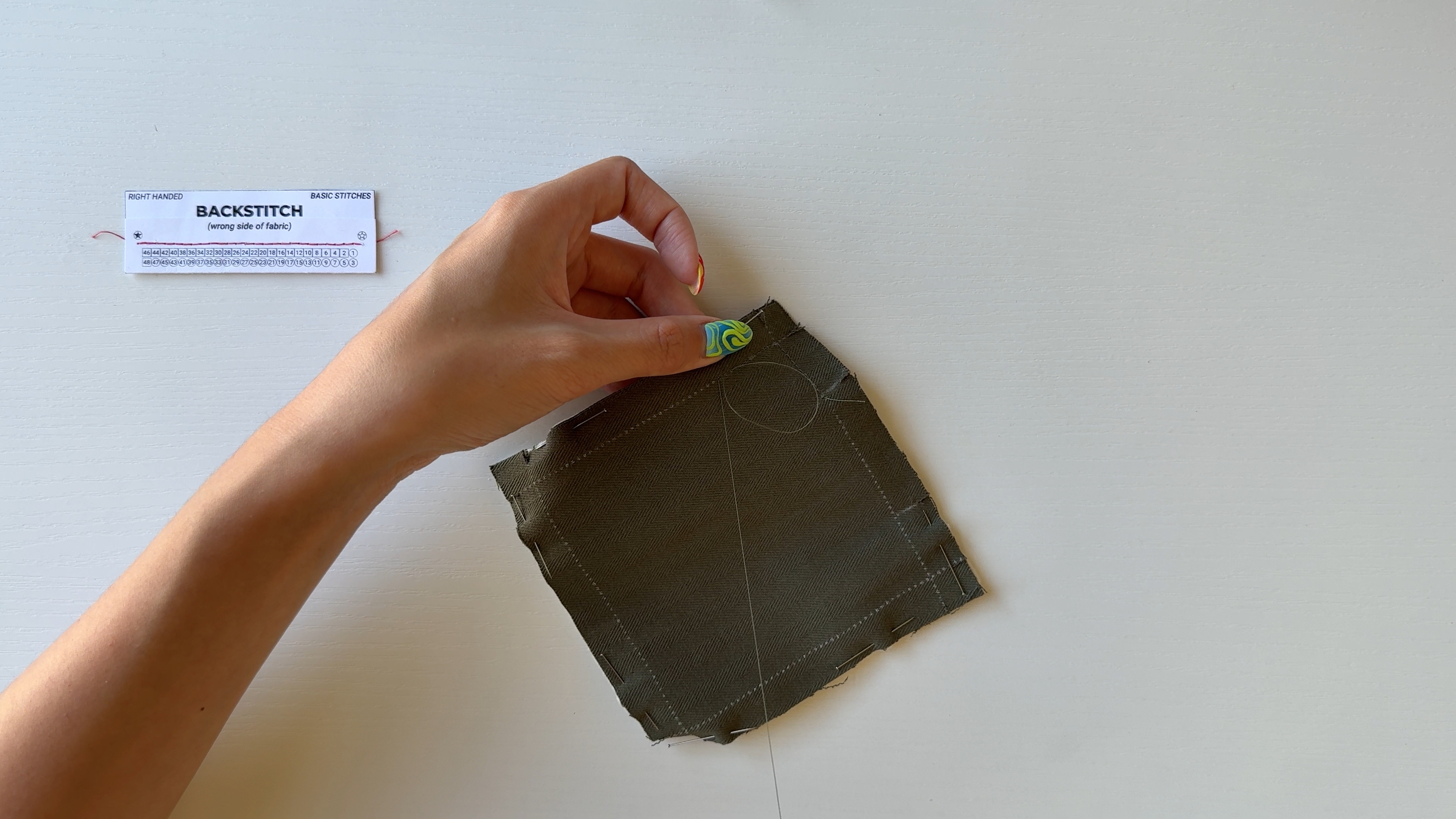 An action shot of hand sewing a fabric coaster