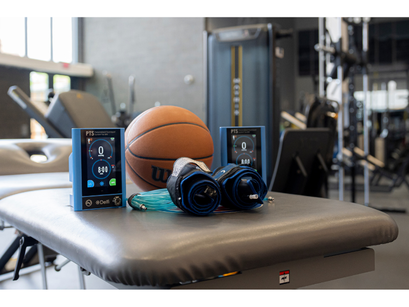 Blood Flow Restriction (BFR) training equipment with Delfi device, cuffs, and basketball – used in strength and rehab training.