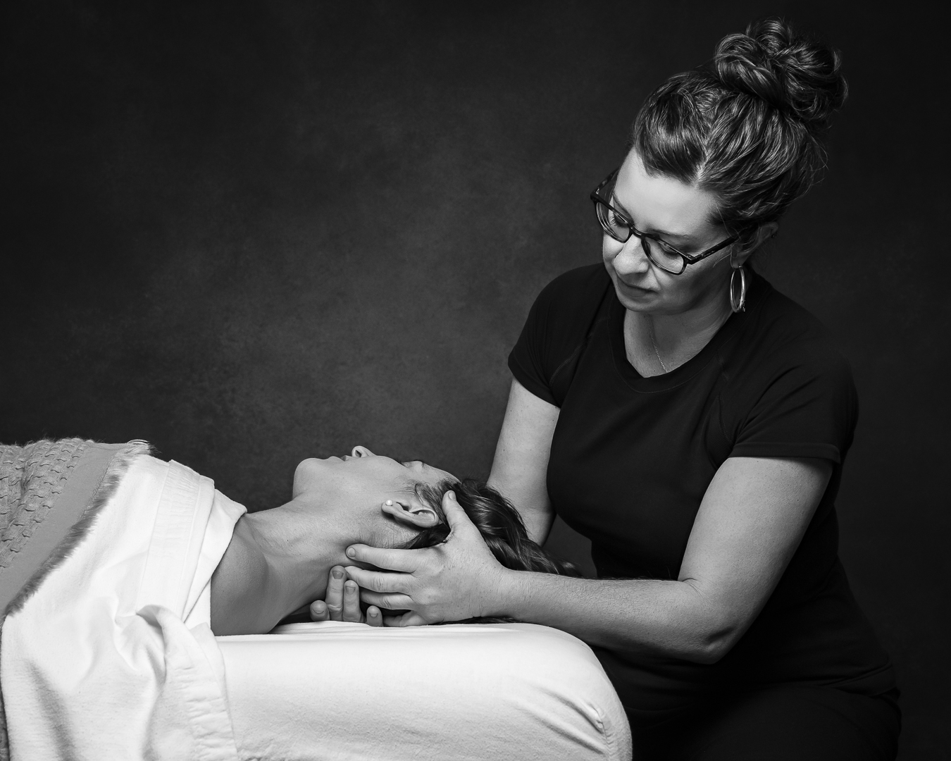 woman massaging the scalp of a woman on a massage table