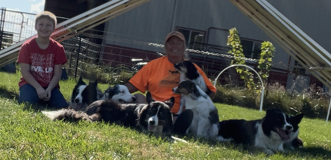 Lisa Schmit sitting outdoors with her six dogs