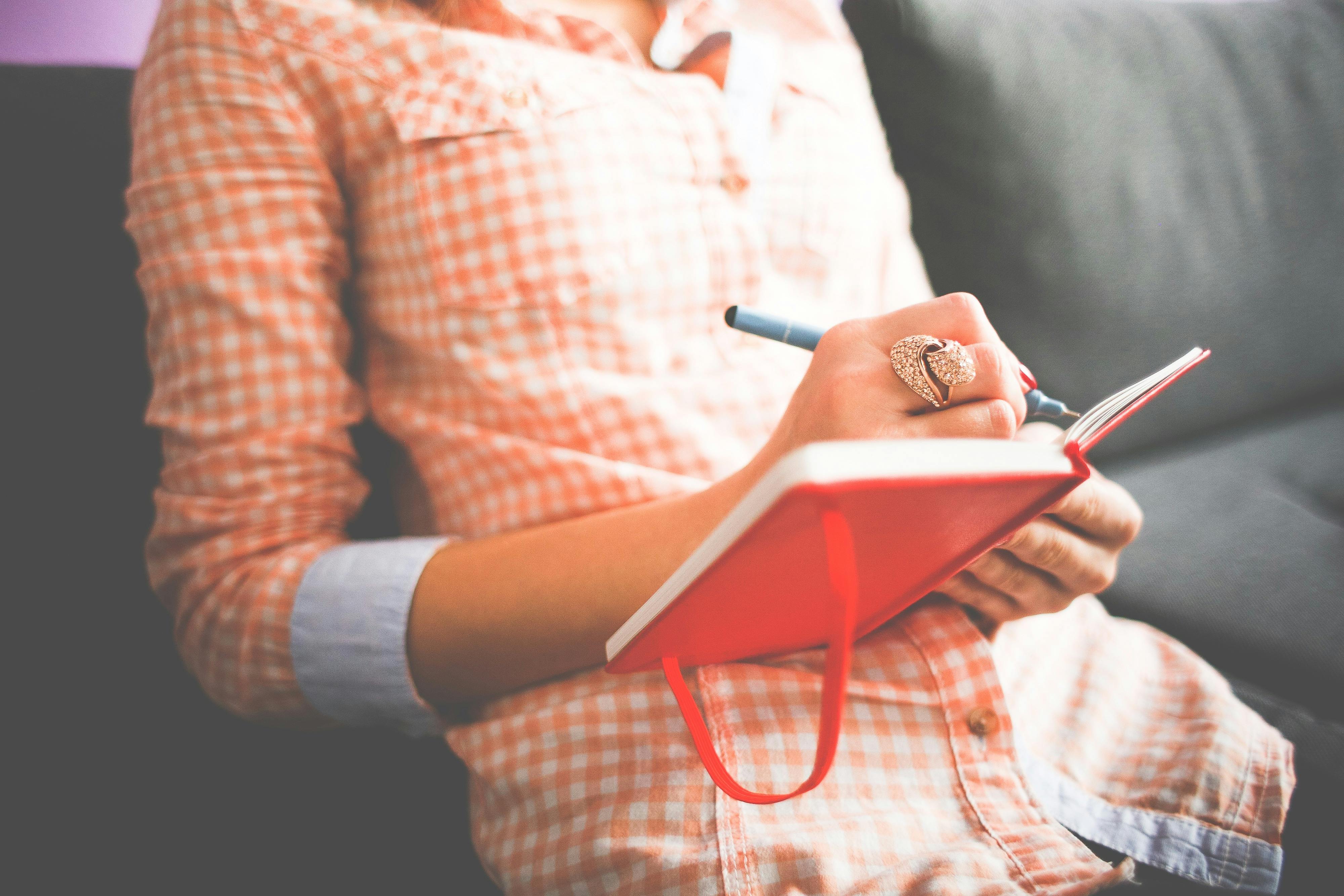 a person is seen journaling on a couch