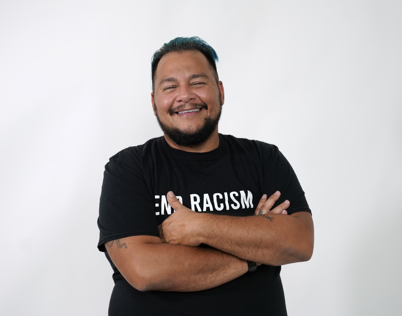 Jack Knoxville is an Afro Latino Trans man with medium brown skin wearing a black shirt that reads 