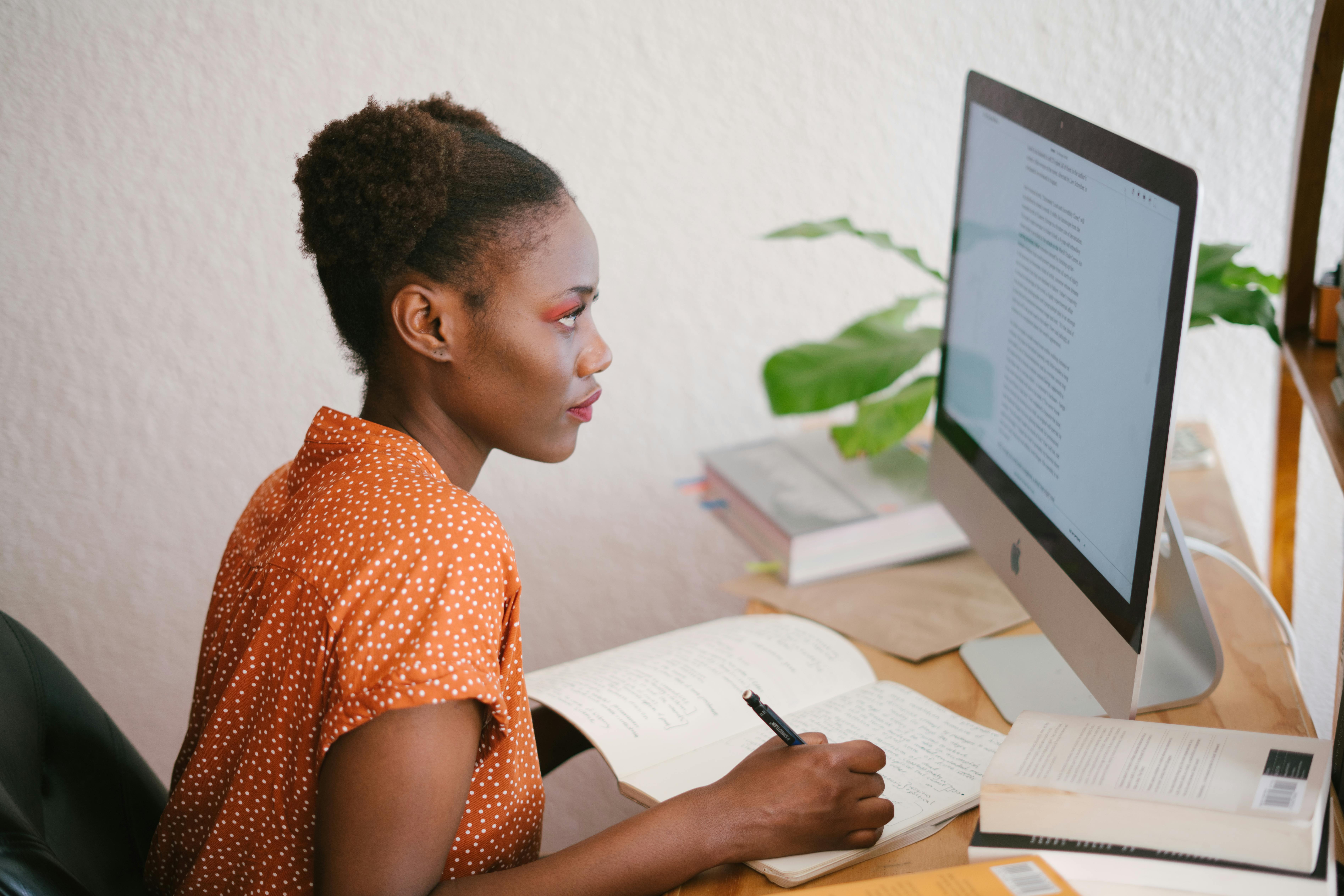 A dark skinned femme person is seen presumably learning online